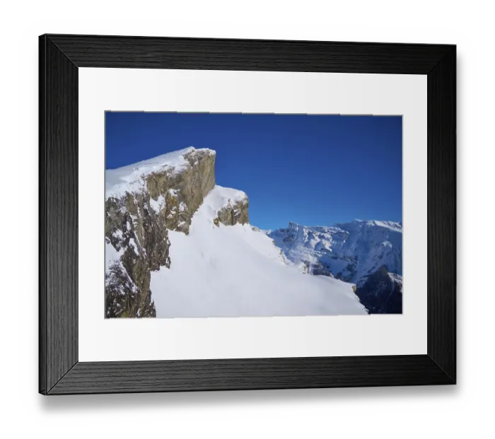 Framed Print : Mountain peak with snow-covered rocks under a clear blue sky