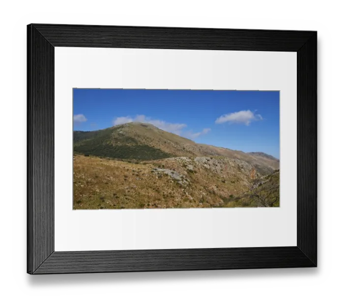 Framed Print : Sunny sky over a barren mountain landscape with green vegetation