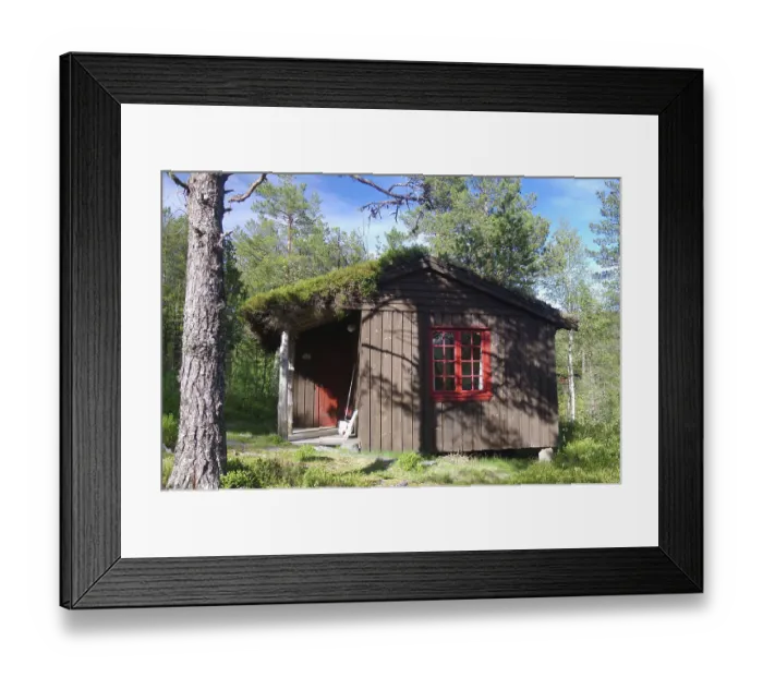 Framed Print : Small rustic wooden hut with a red window and a door in a green forest