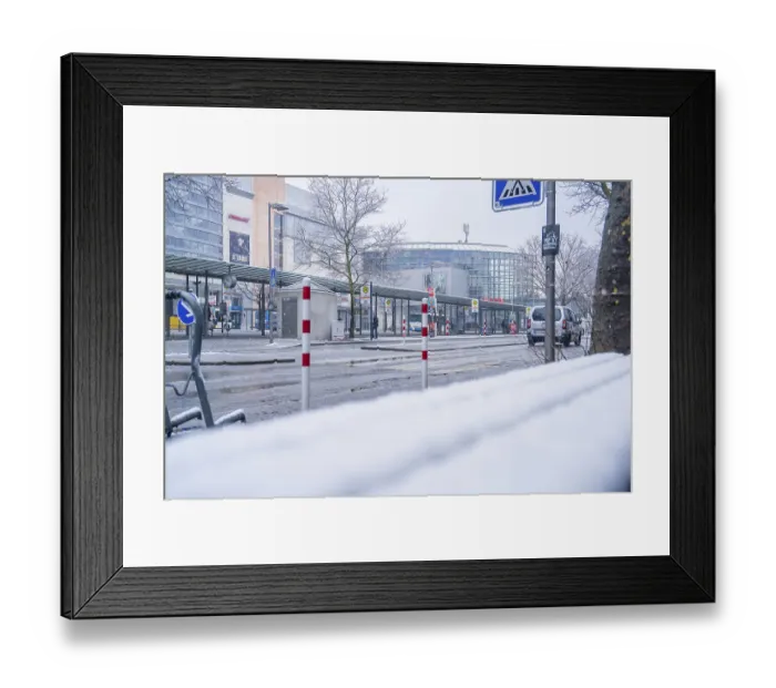 Framed Print : Snowy, empty bus stop in front of a modern building in the city