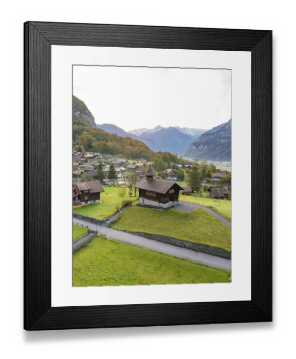 Framed Print : Picturesque Alpine village in a valley surrounded by green hills and majestic mountains