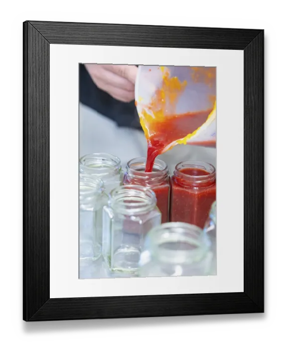 Framed Print : Red liquid is poured from a measuring cup into empty jars