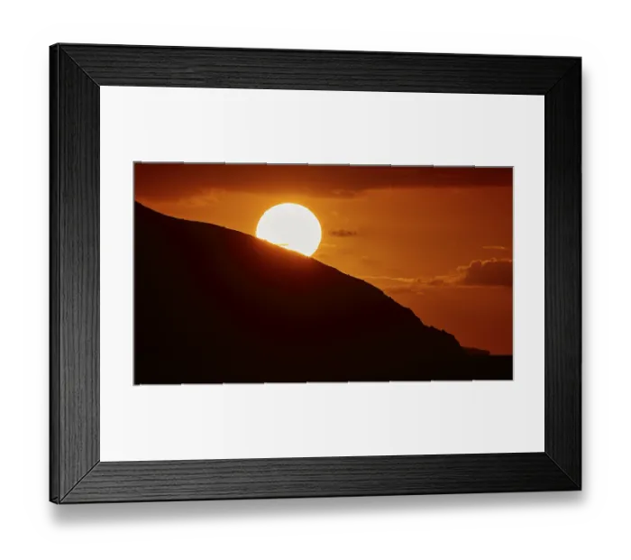 Framed Print : Radiant sun over a mountain in an intense orange sky at sunset