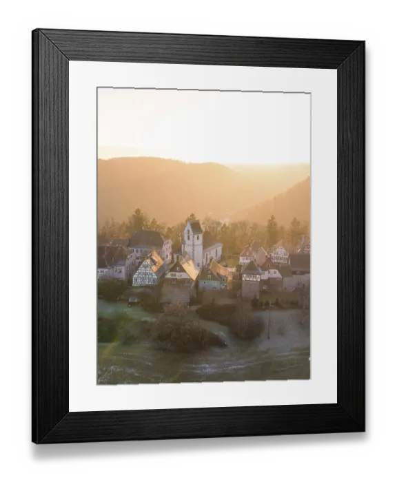 Framed Print : Rural village in the morning sun with church and half-timbered houses against a backdrop of hills