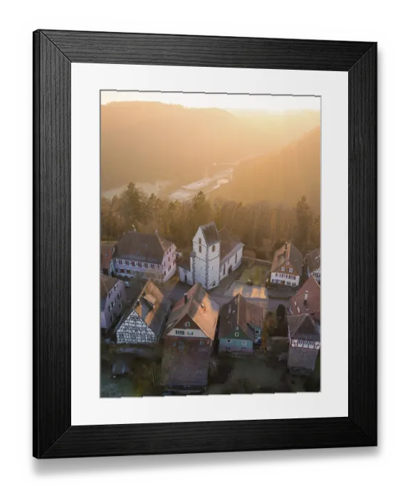 Framed Print : Half-timbered houses and a church in warm sunset light look idyllic and peaceful