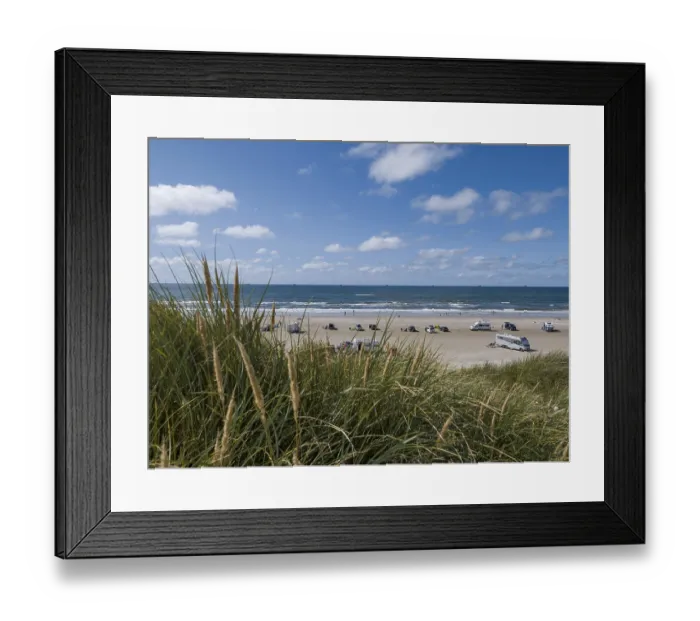 Framed Print : View over dunes to a car beach on the North Sea with campervans by the sea under a blue sky