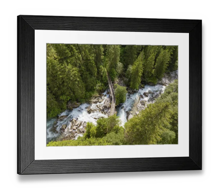 Framed Print : Aerial view of a forest with a river and a narrow wooden bridge surrounded by trees