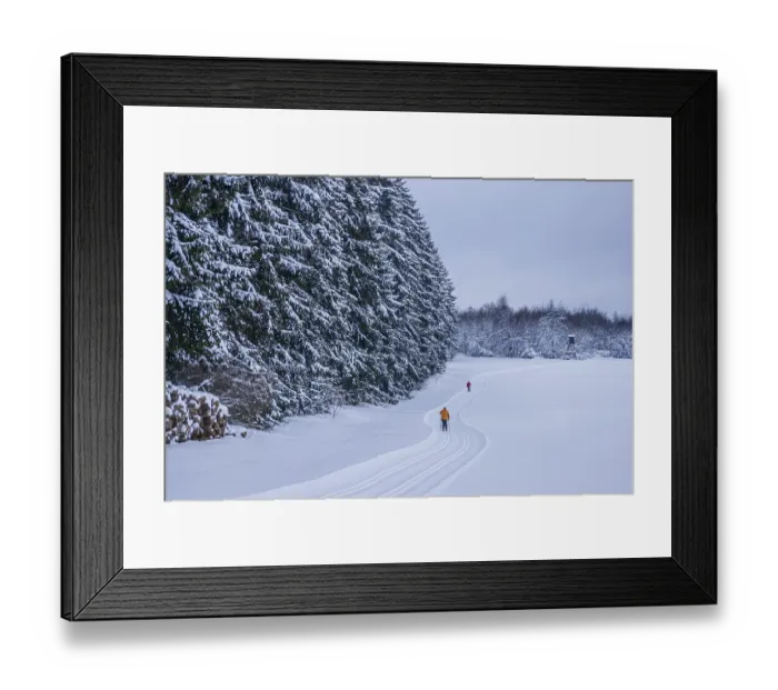 Framed Print : Freshly groomed cross-country trail with cross-country skiers in front of a snow-covered winter forest Framed Print : Freshly groomed cross-country trail with cross-country skiers in front of a snow-covered winter forest