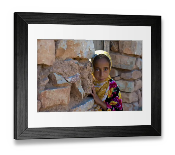 Framed Print : Young girl, berberine, looking curiously from behind a wall