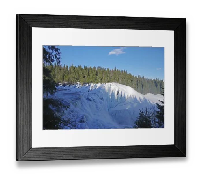 Framed Print : A frozen waterfall in a winter landscape with forest and clear sky