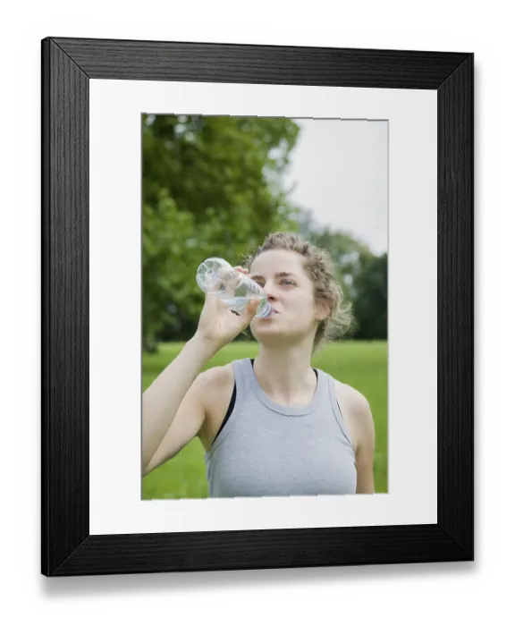 Framed Print : Young woman drinking from a bottle of mineral water after working out
