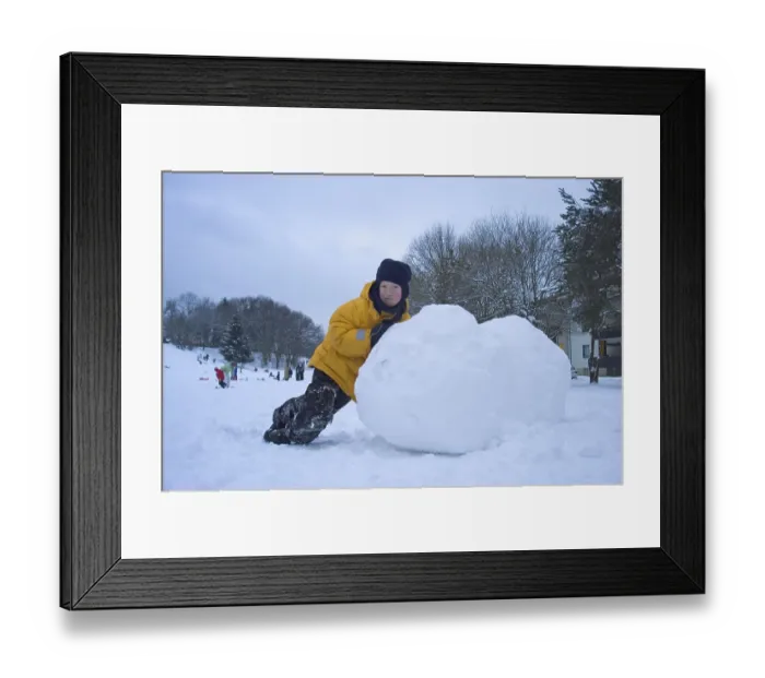 Framed Print : Boy rolling big snow ball