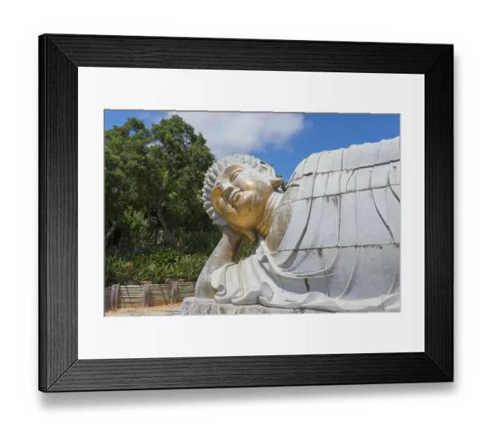 Framed Print : Reclining stone Buddha statue in a peaceful natural setting on a sunny day