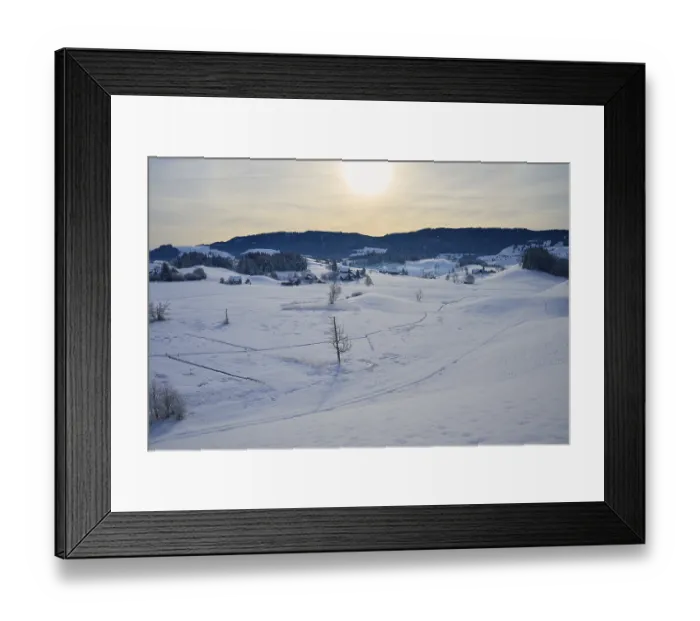 Framed Print : Snowy landscape with farms, rolling hills and mountains in the sunlight