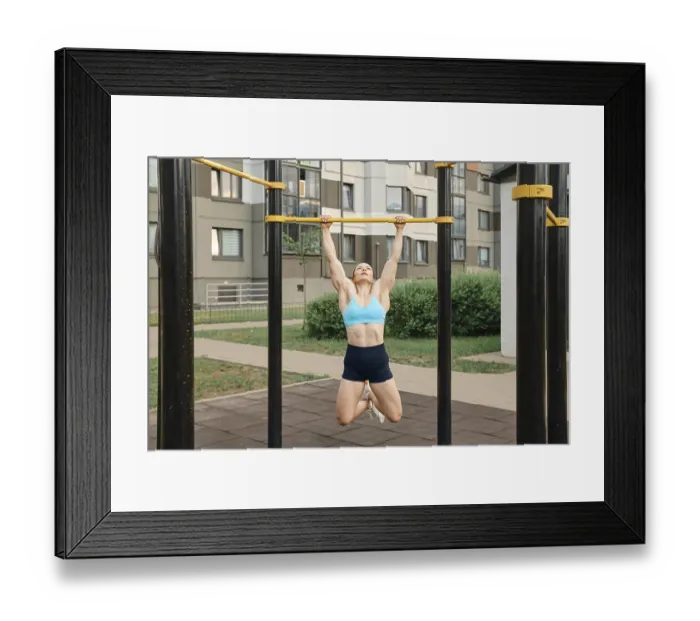 Framed Print : Woman pulls herself up on bar on sports field of residential area