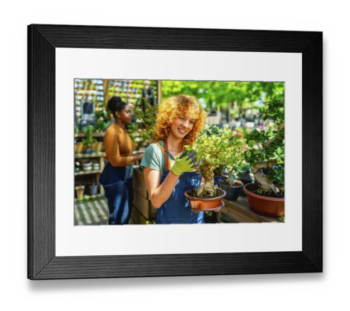 Framed Print : Redhead gardener wearing gloves holding a bonsai tree in a terracotta pot