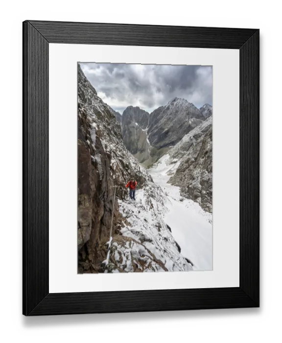 Framed Print : Mountaineer on a rope-secured path in a steep rocky mountain landscape with fresh snow in summer