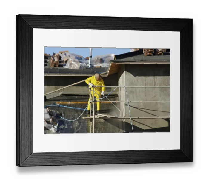 Framed Print : Construction worker pressure washes fresh applied surface of new home exterior