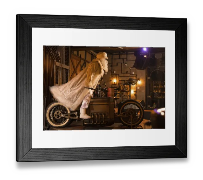 Framed Print : Side view of brutal Santa Claus in white clothes standing on vintage motorbike in grunge rock bar