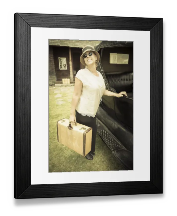 Framed Print : Happy 1920s dressed girl holding suitcase next to vintage car and cabin