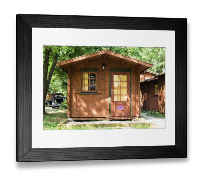 Framed Print : Wooden bungalows on campsite camping. Green trees