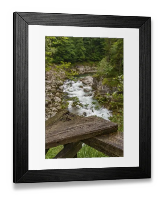 Framed Print : A wooden railing in the foreground with a view of a flowing mountain stream and rocks