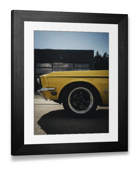 Framed Print : Side view of a yellow classic car in front of a modern garage in sunlight
