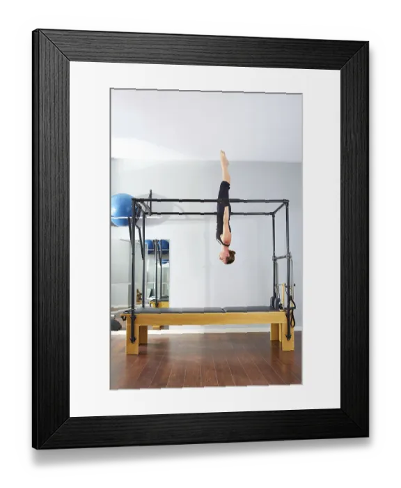 Framed Print : Pilates woman in cadillac acrobatic upside down balance reformer exercise at gym