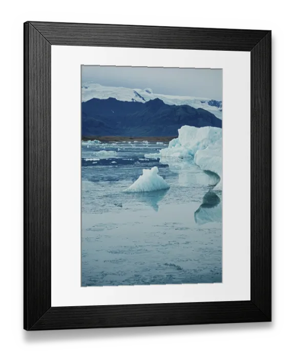 Framed Print : Ice formations float calmly with a mountainous backdrop under a cold sky Framed Print : Ice formations float calmly with a mountainous backdrop under a cold sky