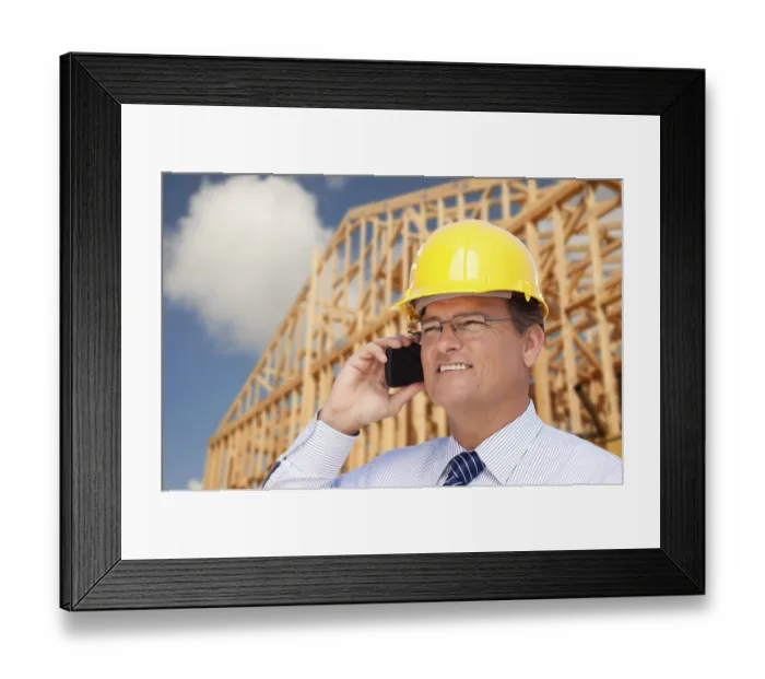 Framed Print : Contractor in hardhat at construction site talks on his cell phone