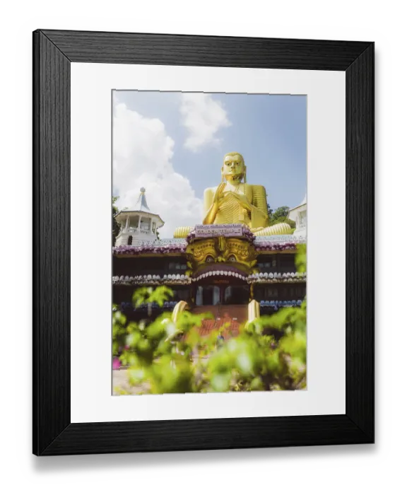 Framed Print : Impressive golden Buddha statue in front of a temple-like background with plants