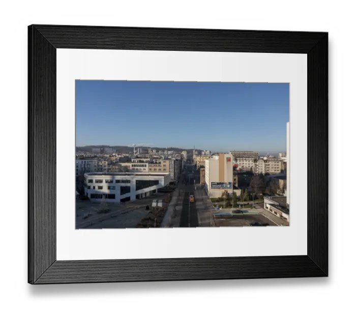 Framed Print : City street flanked by buildings stretching into the distance under a clear sky