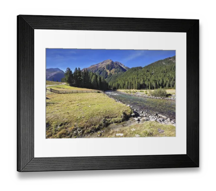 Framed Print : Headwaters Krimml waterfalls. The narrow stream flows between fields and pine forests Framed Print : Headwaters Krimml waterfalls. The narrow stream flows between fields and pine forests