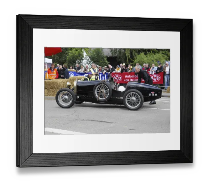 Framed Print : A black historic racing car is pushed by a man at a classic car event