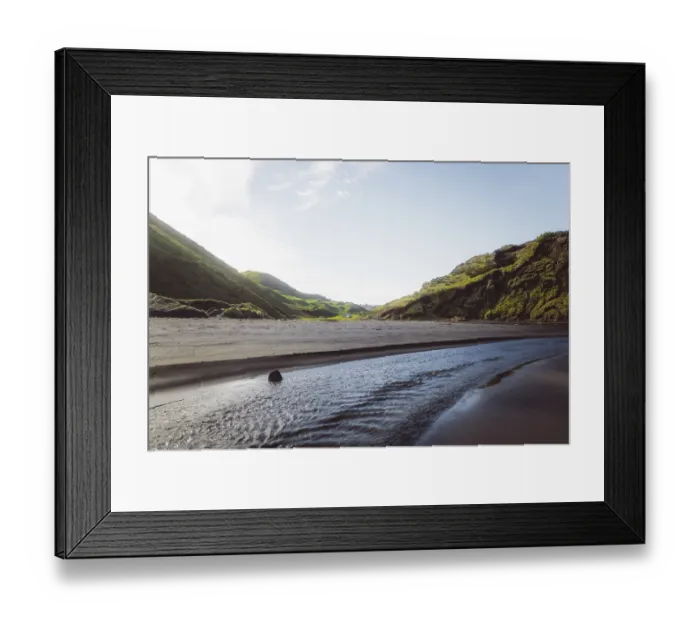 Framed Print : Beach with a flowing river, surrounded by hills and mountains under a blue sky