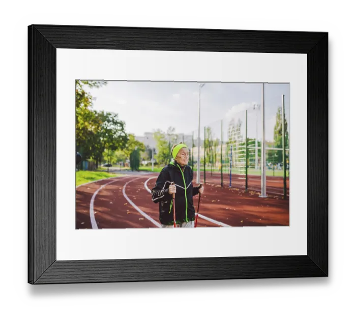 Framed Print : Old woman in sportswear practicing nordic walking outdoors on rubber treadmill in stadium