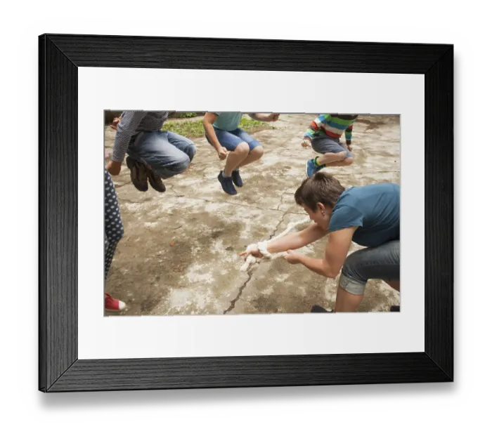 Framed Print : Children play outdoors jumping over the rope