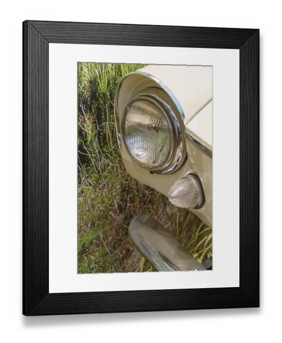 Framed Print : Close-up of a cream-coloured vintage car headlight against a green background