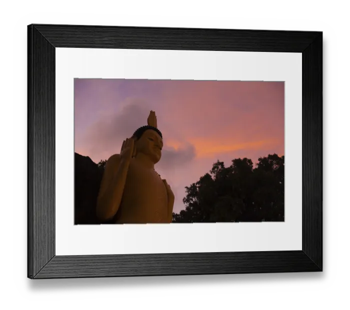 Framed Print : A low angle view of a large golden skinny buddha in front of a beautiful sunset sky at a temple in Unawatuna