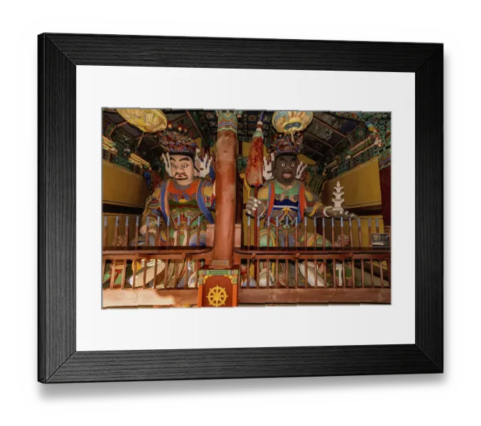 Framed Print : Wood carved statues of two Buddhist deities in covered pavilion at temple