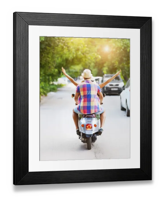 Framed Print : Happy young couple riding a vintage scooter in the street wearing hats