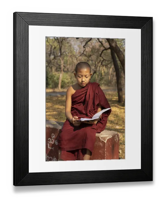 Framed Print : Child monk with red robe reading on a red wall