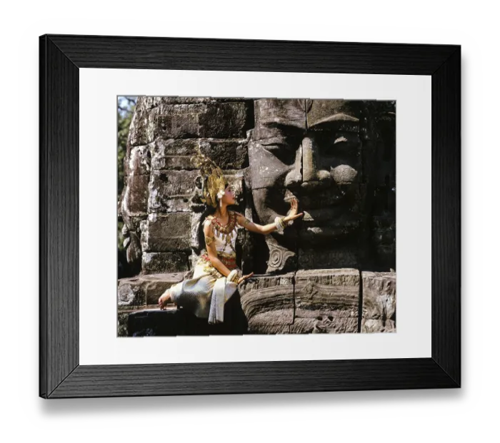 Framed Print : Temple dancer or apsara sitting in front of a face tower at Bayon Temple