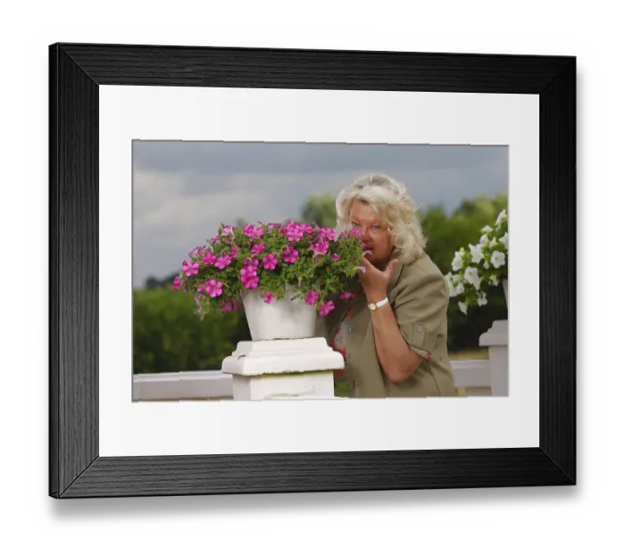 Framed Print : Woman smelling at petunia (Petunia hybride)