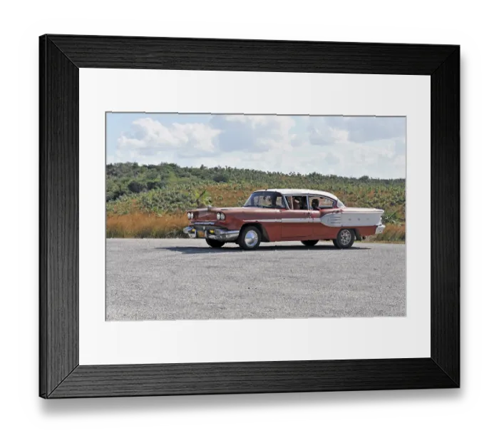 Framed Print : Red vintage car driving on a road through Cuban countryside