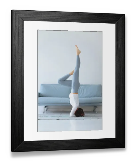 Framed Print : Slim female in sportswear bending aside while practicing yoga near sofa at home Framed Print : Slim female in sportswear bending aside while practicing yoga near sofa at home