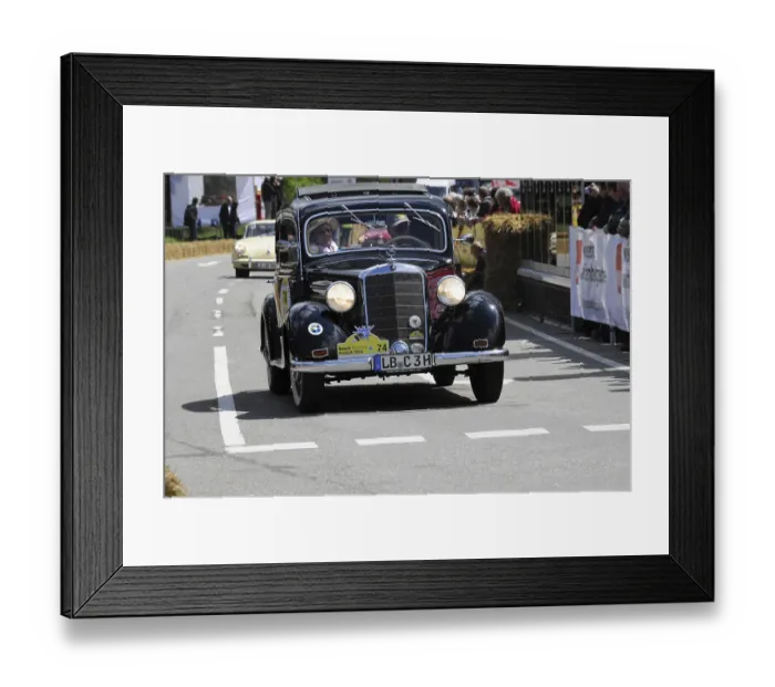 Framed Print : A classic Mercedes vintage car drives past spectators at a sunny road race