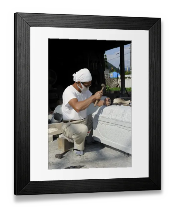 Framed Print : Stonemason chiseling at the base of a stone lamp