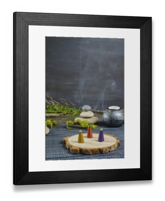 Framed Print : Colorful incense cones on a wooden disk with candles and zen stones stacked on top of them