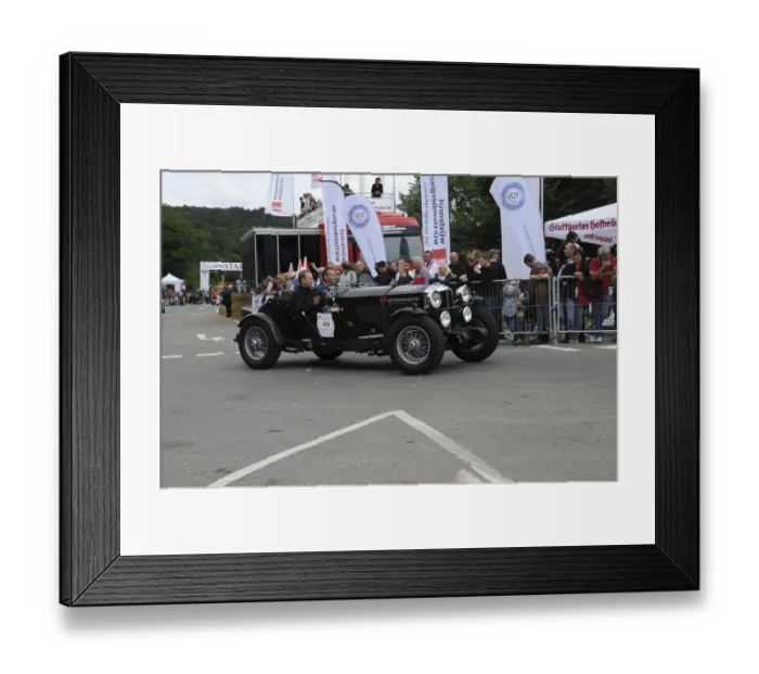 Framed Print : A black vintage car drives past spectators at a racing event